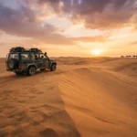 Golden Dubai desert dunes and safari vehicle at sunset